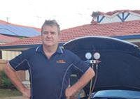 shows a man standing in front of a car with its hood open, and a set of gauges connected to the car's air conditioning system.  